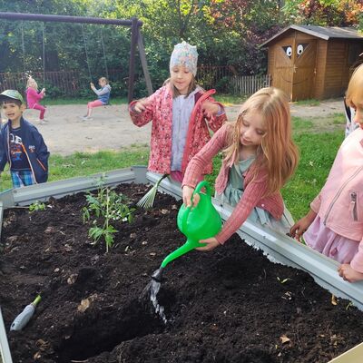 Kinder gießen die Pflanzen