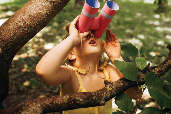 Closeup portrait of little girl looking through a binoculars sea