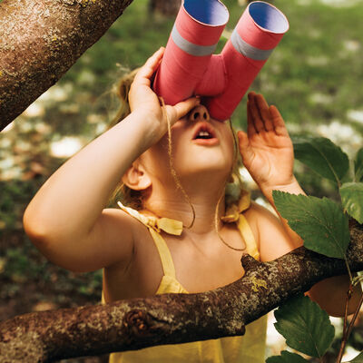 Closeup portrait of little girl looking through a binoculars sea